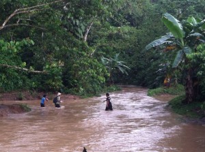 Community members crossing the river by foot. When the water rises they are often stuck waiting hours or days for it to go down.
